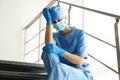 Exhausted doctor sitting on stairs in hospital. Stress of health care workers during COVID-19 pandemic