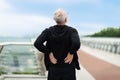 Exhausted elderly sportsman touching lower back, exercising outdoor