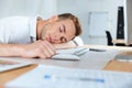 Exhausted fatigued young businessman sleeping on the table