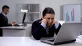 Exhausted female office worker waiting for important e-mail, looking at laptop Royalty Free Stock Photo