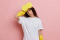 Exhausted housekeeper, she stands and looks tired, against pink wall