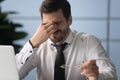 Exhausted male employee suffering from strong headache