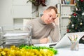 Exhausted male office worker sitting at his desk in Christmas decorated office