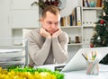 Exhausted male office worker sitting at his desk in Christmas decorated office