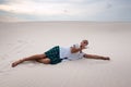 Exhausted man lies on the sand and drinks the remains of water Royalty Free Stock Photo