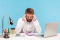 Exhausted man office worker massaging temples feeling unbearable headache sitting at workplace with laptop on desk, solving hard