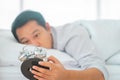 Exhausted man sleeping in bed tired by waking up to the alarm clock ring in the morning suffering from insomnia Royalty Free Stock Photo