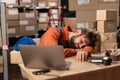 Exhausted man sleeping on his desk near laptop tired of overworking in warehouse. Workaholic suffering from chronic Royalty Free Stock Photo