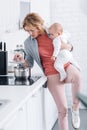 exhausted mother holding adorable infant child and cooking