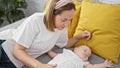 Exhausted mother lying on bed, lovingly watchful while her baby daughter sleeps in bedroom amidst the wholesome family background