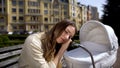 Exhausted mother sleeping on newborn carriage sitting on bench, exhaustion