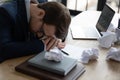 Exhausted office worker resting head on work desk with laptop