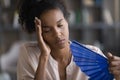 Exhausted overheated young african woman waving paper fan. Royalty Free Stock Photo