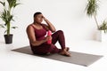 Exhausted overweight black lady sitting on fitness mat