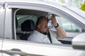 Exhausted overweight man driver sit inside car hot weather puts bottle of water to overheat forehead