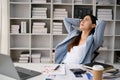 Exhausted Asian businesswoman putting her hands over head, resting in her office