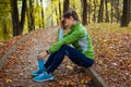 Exhausted runner having rest after workout in autumn park. Tired woman holding water bottle. Sportive lifestyle Royalty Free Stock Photo