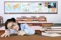 Exhausted schoolgirl with books on the table