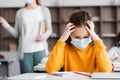 exhausted schoolgirl in medical mask touching