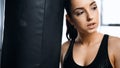 exhausted sportswoman leaning on punching bag