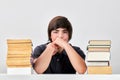 Exhausted stressed and angry teenage school boy sitting at the table between pile of books Royalty Free Stock Photo
