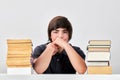 Exhausted stressed and angry teenage school boy sitting at the table between pile of books