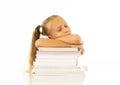 Exhausted sweet cute blonde girl sleeping on a pile of schoolbooks after being studying hard isolated on a withe background in too Royalty Free Stock Photo