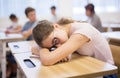 Exhausted teen girl sleeping at desk during lesson
