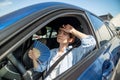 Exhausted middle aged woman drives car waves blue fan suffers from stuffiness in traffic jam. Royalty Free Stock Photo