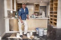 Male painter holding wet paintbrush standing in messy home kitchen fixer upper remodel project, dripping paint cans everywhere Royalty Free Stock Photo