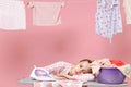 Exhausted tired young woman housewife in checkered shirt dry clothes on rope and ironing clean clothes while doing Royalty Free Stock Photo