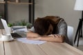 Exhausted unmotivated young female worker fallen asleep at table.