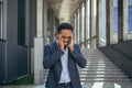 Exhausted young African American business man office worker stand outdoors. stressed overworked black male with a headache Royalty Free Stock Photo