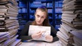 Exhausted young business woman office employee at the desk working late at night overloaded with paperwork. Female on Royalty Free Stock Photo