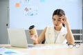 Exhausted young businesswomen holding coffee paper cups are stressed and tired having headaches at the office desk. Asian woman Royalty Free Stock Photo