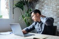 Exhausted young Caucasian male worker sit at desk massage neck suffer from strain spasm muscles. Tired unwell man overwhelmed with Royalty Free Stock Photo