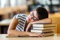 Exhausted young female studying and preparing for exam in college library. Education people concept Royalty Free Stock Photo