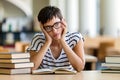 Exhausted young female studying and preparing for exam in college library. Education people concept Royalty Free Stock Photo