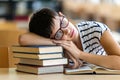 Exhausted young female studying and preparing for exam in college library. Education people concept Royalty Free Stock Photo