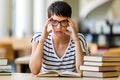 Exhausted young female studying and preparing for exam in college library. Education people concept Royalty Free Stock Photo