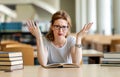 Exhausted young female studying and preparing for exam in college library. Education people concept Royalty Free Stock Photo