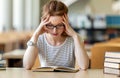 Exhausted young female studying and preparing for exam in college library. Education people concept Royalty Free Stock Photo