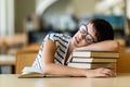 Exhausted young female studying and preparing for exam in college library. Education people concept Royalty Free Stock Photo