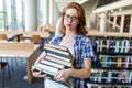 Exhausted young female studying and preparing for exam in college library. Education people concept Royalty Free Stock Photo