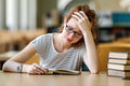 Exhausted young female studying and preparing for exam in college library. Education people concept Royalty Free Stock Photo