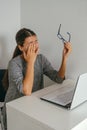 Exhausted young woman holding glasses and touching her eyes, overworking and eye fatigue from computer concept Royalty Free Stock Photo