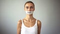 Exhausting diet concept, miserable slim woman with taped mouth looking at camera Royalty Free Stock Photo