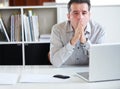 Exhaustion in the workplace. Portrait of a stressed out-looking businessman sitting in front of his laptop. Royalty Free Stock Photo