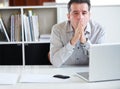 Exhaustion in the workplace. Portrait of a stressed out-looking businessman sitting in front of his laptop. Royalty Free Stock Photo