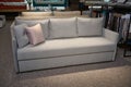 Exhibition of upholstered furniture in showroom- sofas, beds, settees. Beautiful comfortable large sofa, settee with pillows near